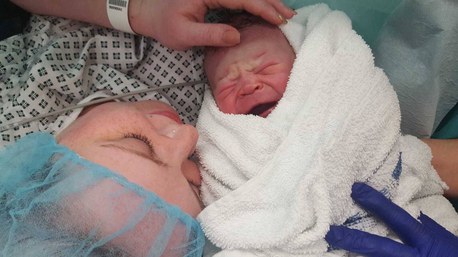 Heather lying down after a c-section, holding her newborn baby