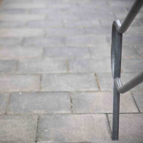 Grey paving slabs viewed from steps, a metal handrail to the right