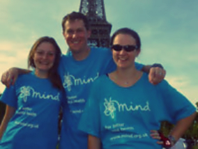 Mark in front of the Eiffel Tower wearing a Mind t-shirt with his arms around two others wearing the same top