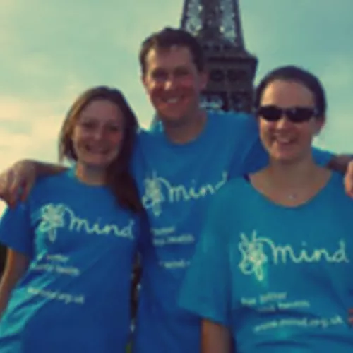 Mark in front of the Eiffel Tower wearing a Mind t-shirt with his arms around two others wearing the same top