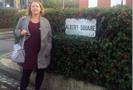 Jenni standing next to a street sign saying "Albert Square"