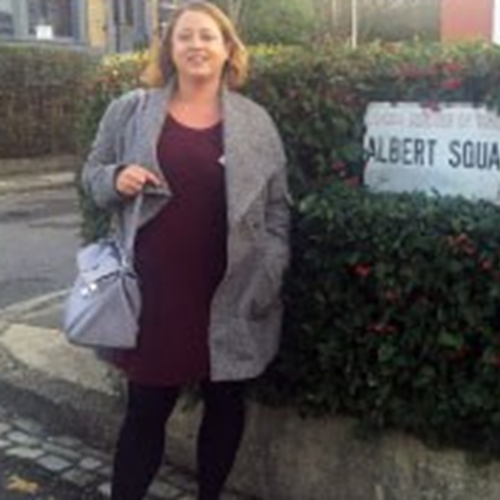 Jenni standing next to a street sign saying "Albert Square"