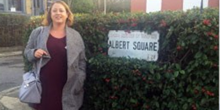 Jenni standing next to a street sign saying "Albert Square"
