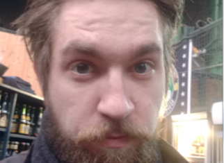 Young White man with a blonde beard looking into the camera.