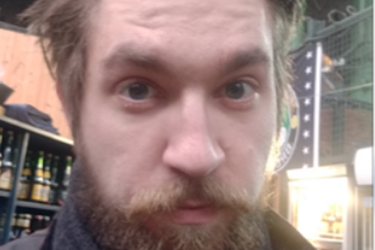 Young White man with a blonde beard looking into the camera.