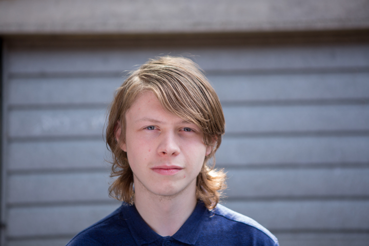Young person staring at camera in front of garage