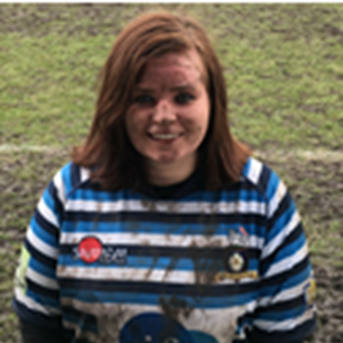 Photo of Laura smiling and standing on a rugby field