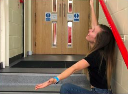 Girl sitting on stairs with arms wide open as if presenting something