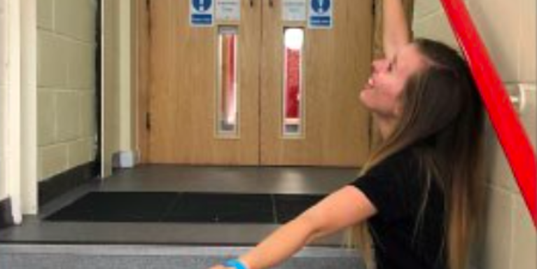 Girl sitting on stairs with arms wide open as if presenting something