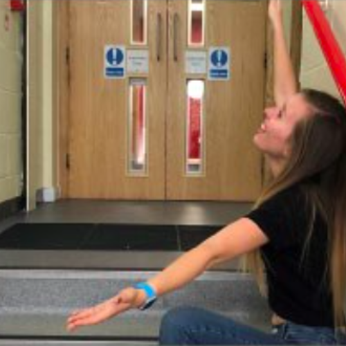 Girl sitting on stairs with arms wide open as if presenting something