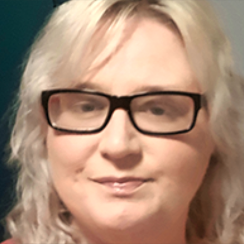 Girl with blonder hair and thick black framed glasses facing the camera