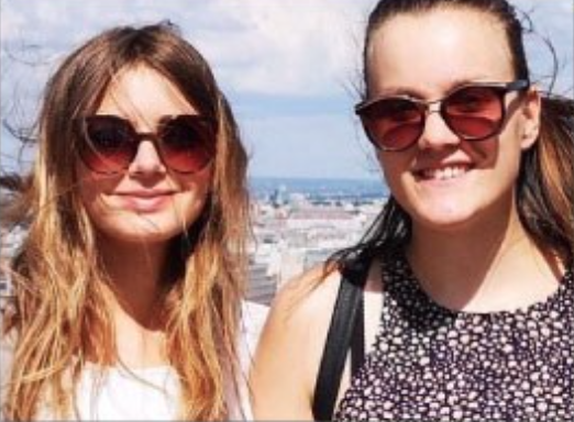 Two teenage girls looking the camera wearing sunglasses on a sunny day