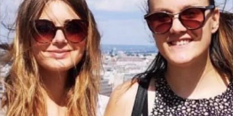 Two teenage girls looking the camera wearing sunglasses on a sunny day