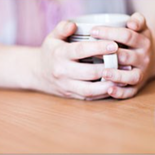 Hands holding a mug sitting on a desk
