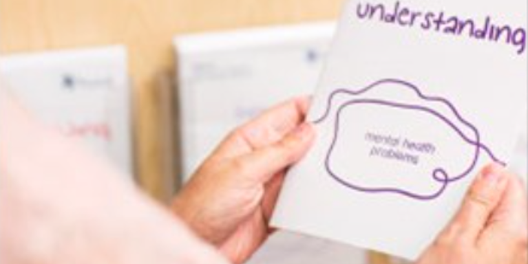 over the shoulder shot of person holding a leaflet about understanding mental health problems