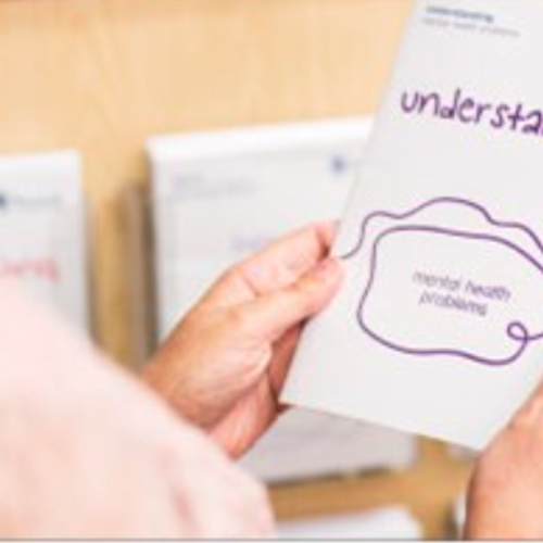 over the shoulder shot of person holding a leaflet about understanding mental health problems