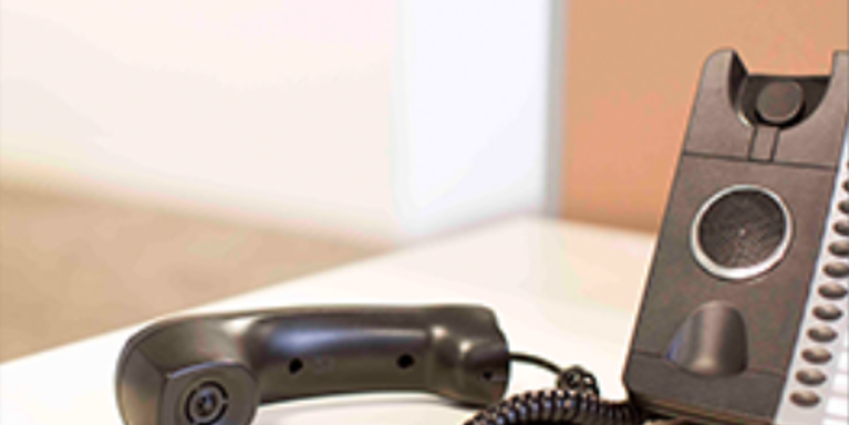 A landline phone of the holder and lying next to it on a desk