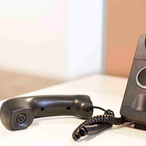 A landline phone of the holder and lying next to it on a desk