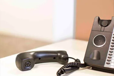 A landline phone of the holder and lying next to it on a desk A landline phone of the holder and lying next to it on a desk