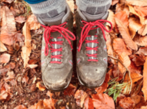 On the autumn leave-covered floor, Nikki's walking boots are worn and laced with bright red laces.