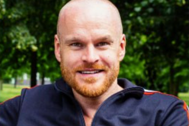 male with bald head and ginger beard smiling 