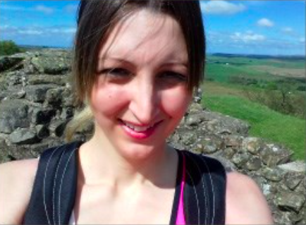female smiling with rocky terrain behind her