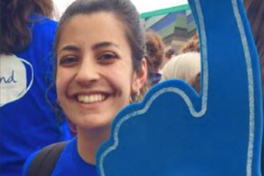female holding a blue foam finger wearing a blue top with mind logo