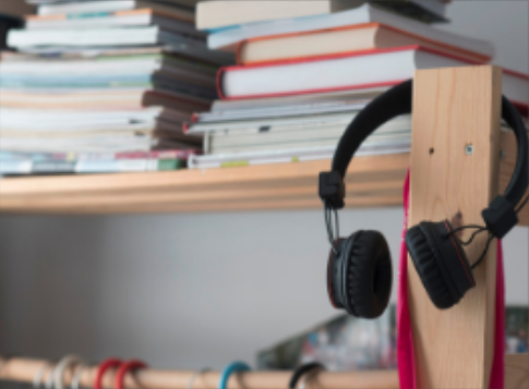 Headphones hung on wooden shelving with books on it