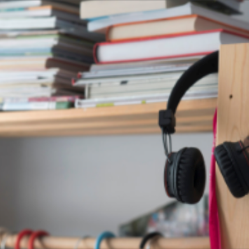 Headphones hung on wooden shelving with books on it
