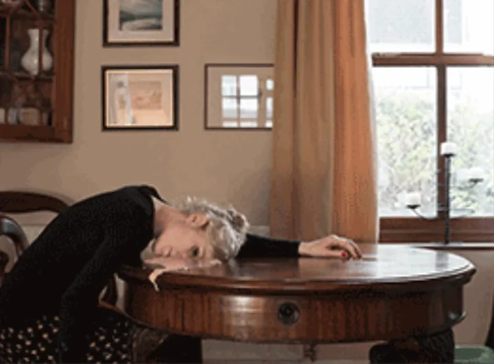 Female sitting on a chair, lying her arms and arm on the table in front Female sitting on a chair, lying her arms and arm on the table in front
