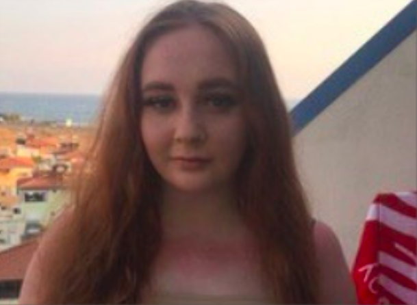 Female smiling which houses and the sed behind her