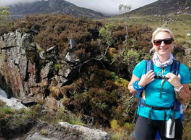 female wearing backpack standing next to rocky terrain