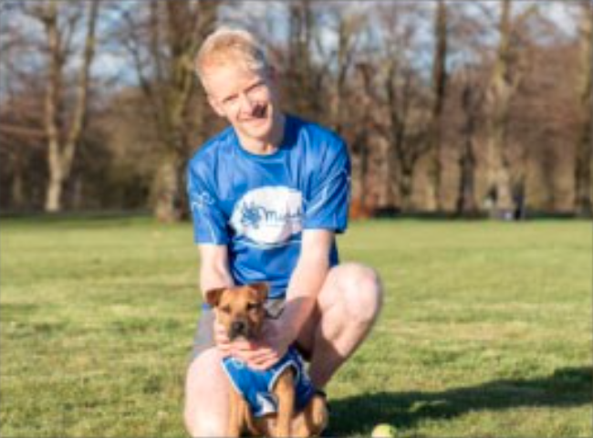 males kneeling behind and holding a small brown dog lovingly
