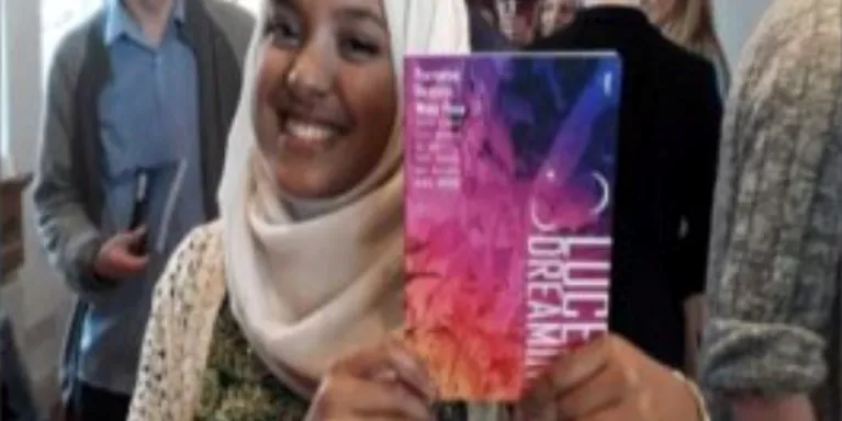 female holding a brightly coloured textbook