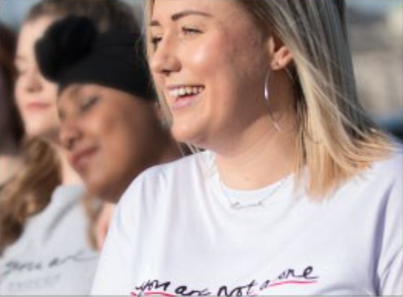 female turned to the left laughing with females behind her also smiling