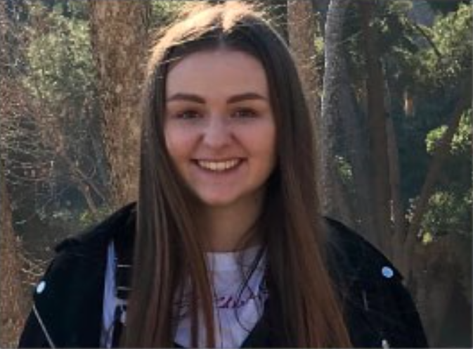 female smiling with forest behind