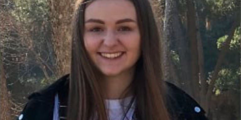 female smiling with forest behind