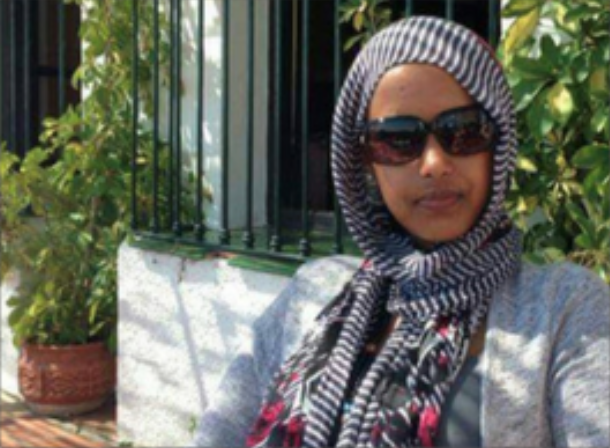 female in the sun wearing sunglasses and a striped headscarf 