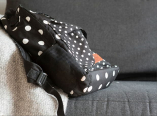 black and white spot rucksack on a grey sofa