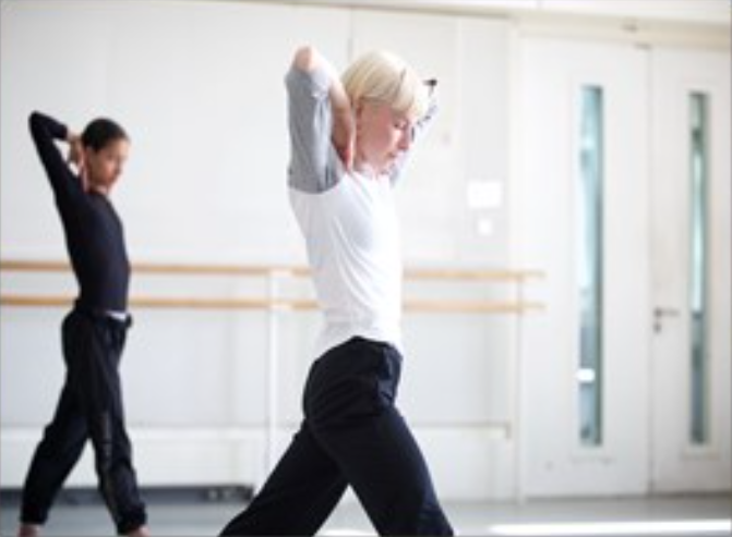 two females doing the same dance pose in a dance studio