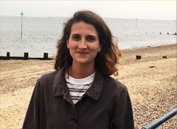 Female standing in front of a beach on a bleak day