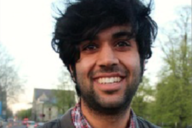 male with very black, thick hair smiling