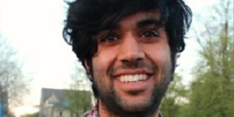male with very black, thick hair smiling