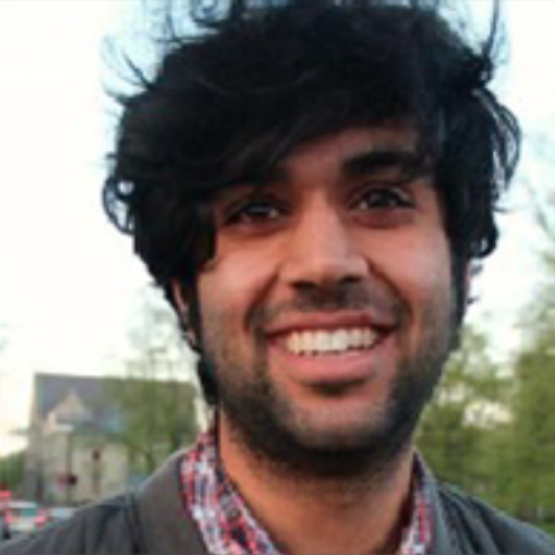 male with very black, thick hair smiling