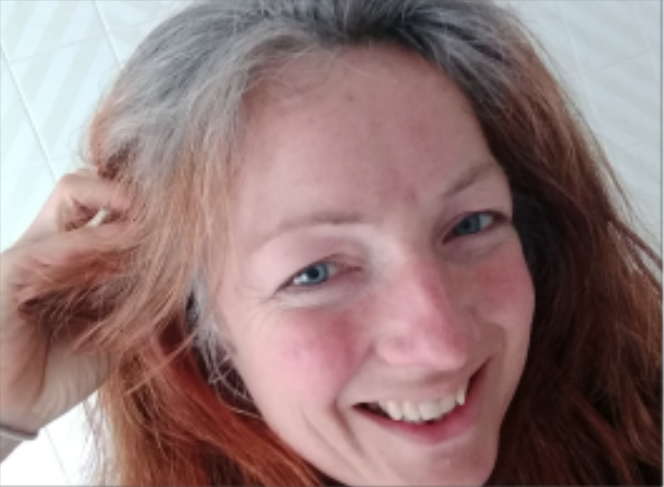 female with her grey hair growing out after being dyed auburn