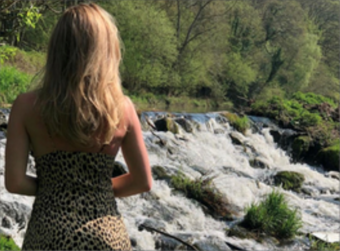 female with her back to the camera, looking at white water rafts