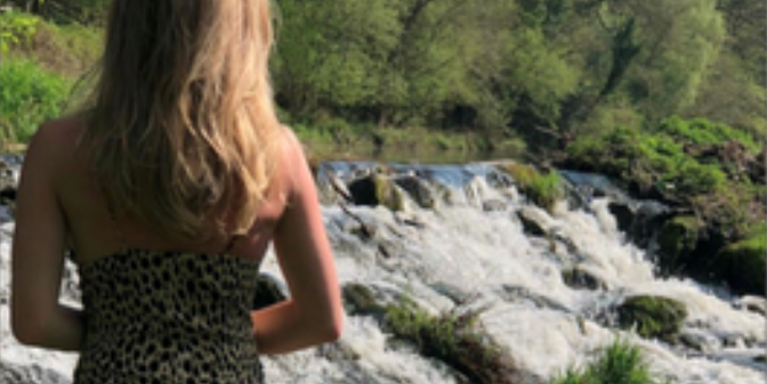 female with her back to the camera, looking at white water rafts