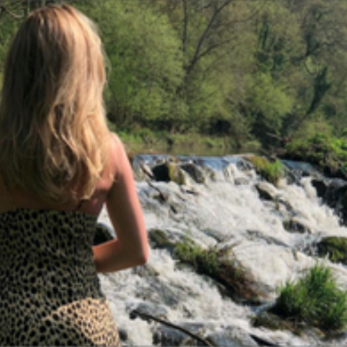 female with her back to the camera, looking at white water rafts