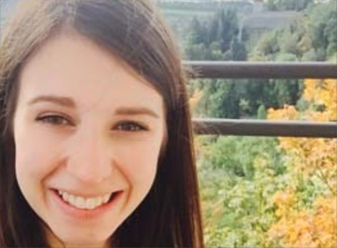 female smiling with many trees behind her