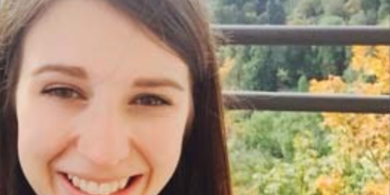 female smiling with many trees behind her